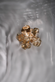 A gold metal flower swimwear clip.