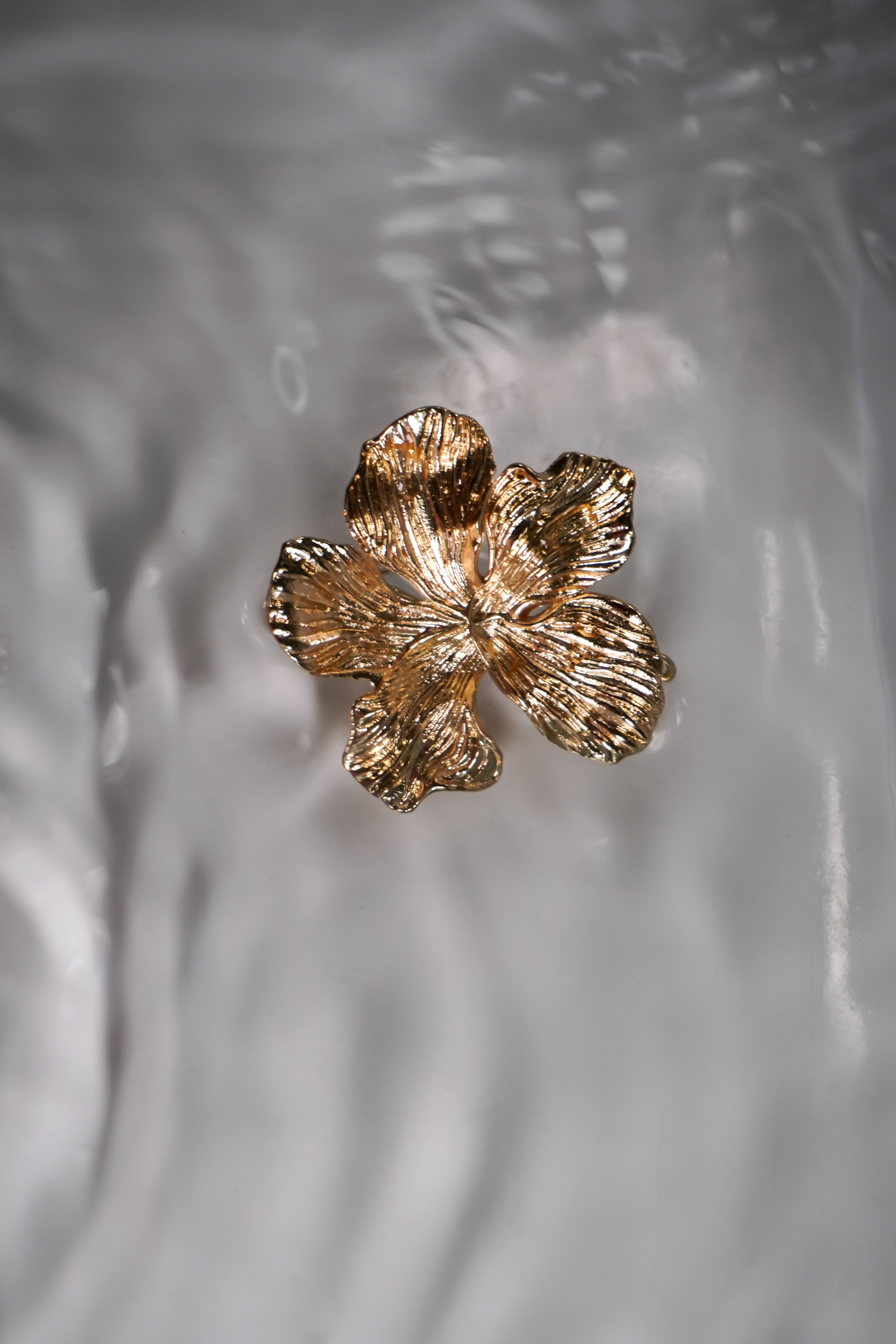 A gold metal flower swimwear clip.